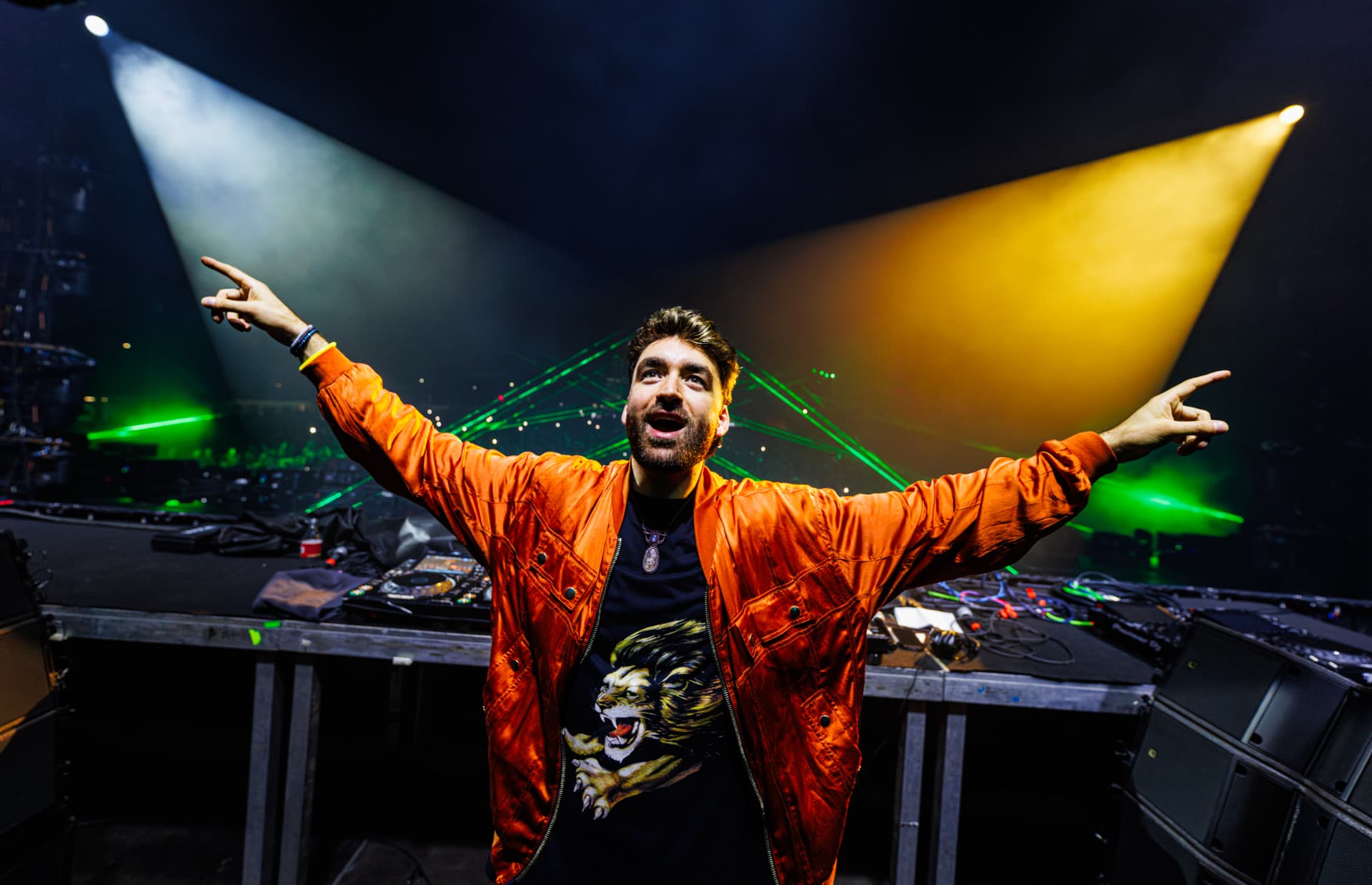 Oliver Heldens na pódiu s lasery v oranžové bundě